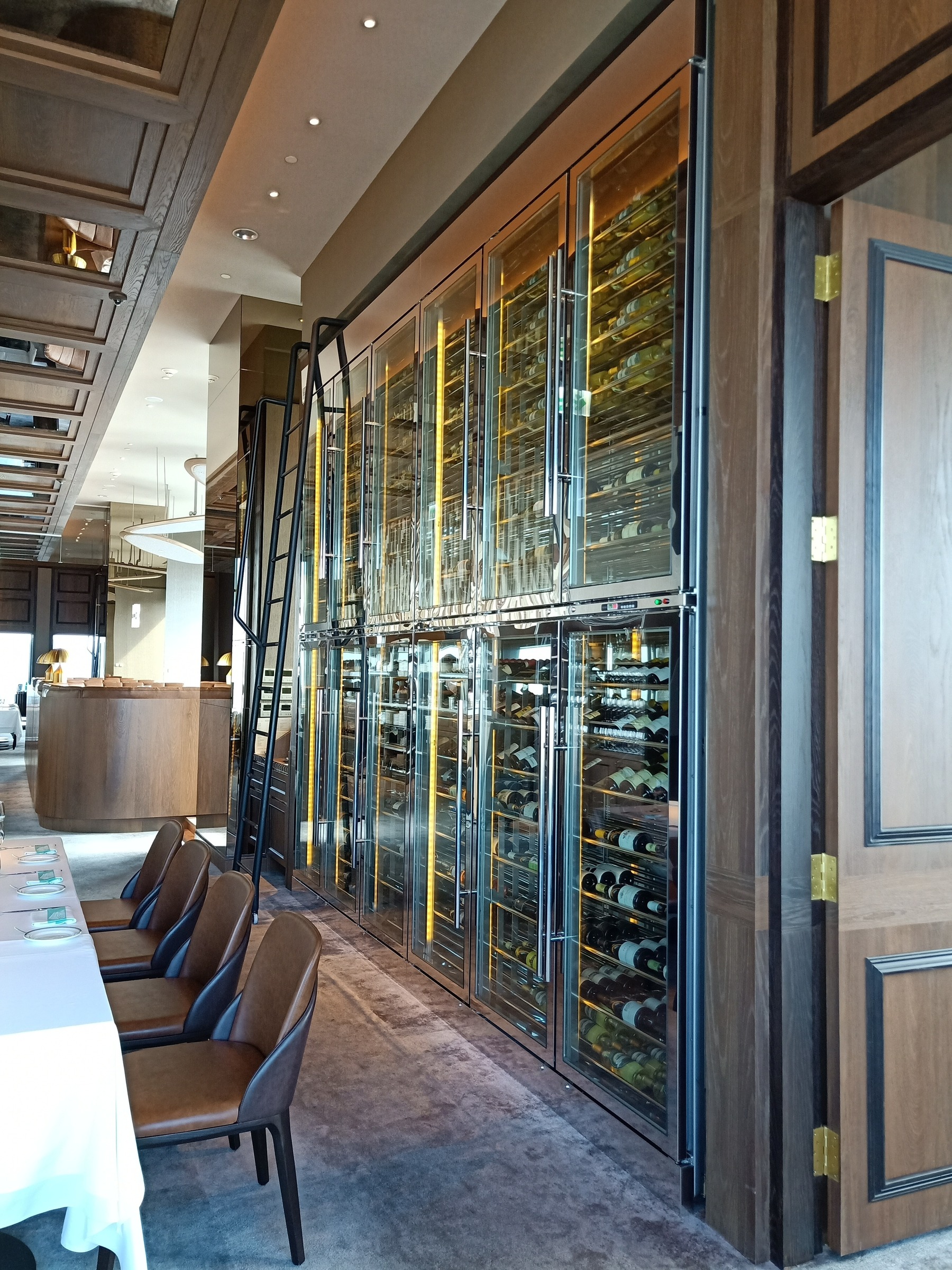 餐廳整面嵌入式葡萄酒櫃牆，含滑軌取酒梯